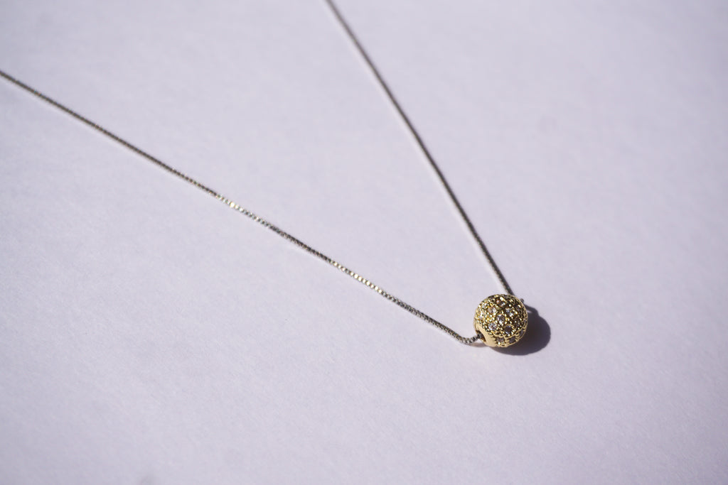 Collar con cadena plateada y bolitas de zirconias doradas