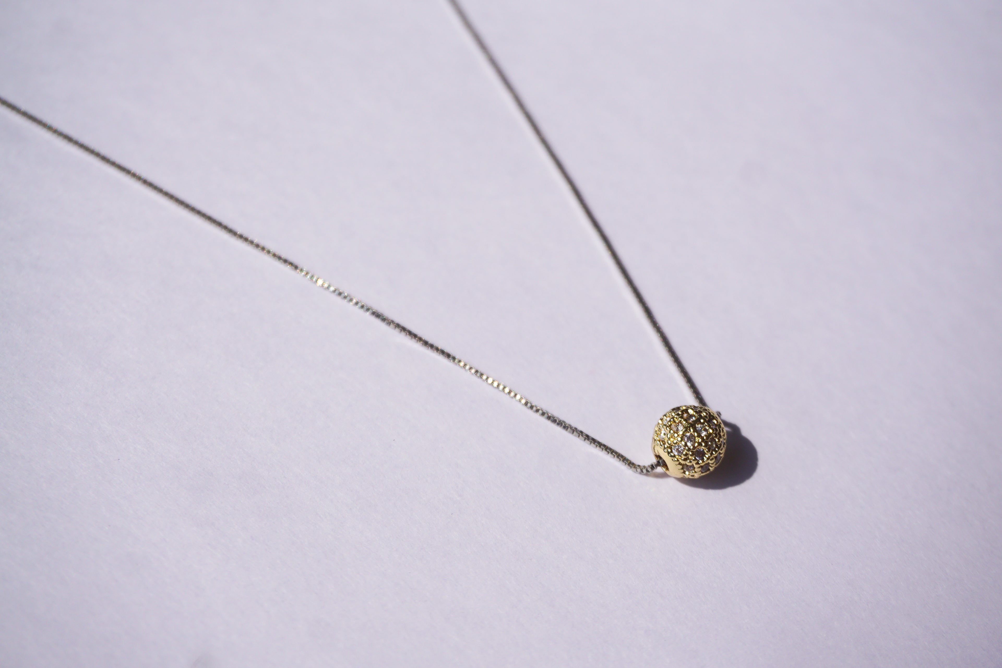 Collar con cadena plateada y bolitas de zirconias doradas