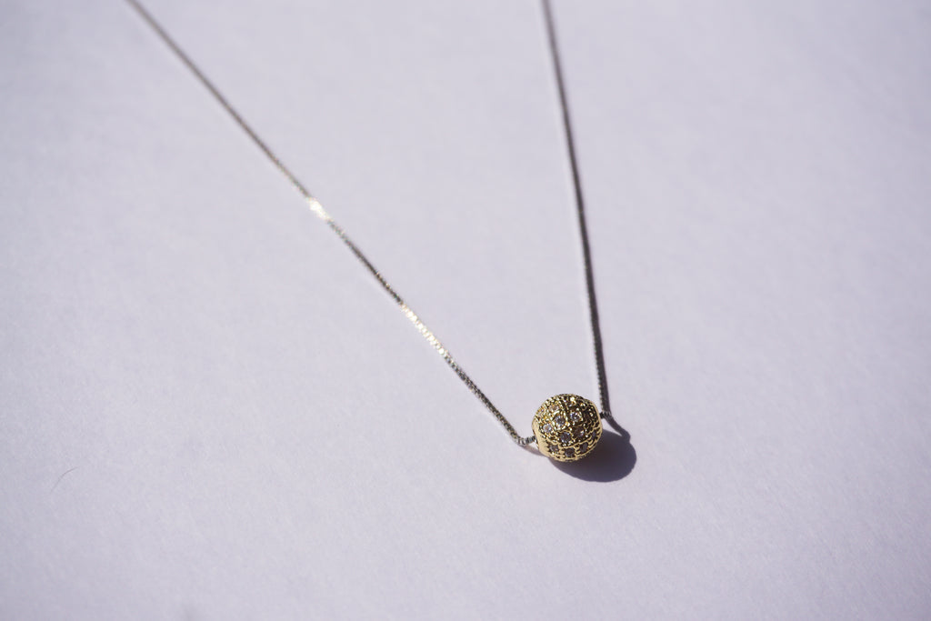 Collar con cadena plateada y bolitas de zirconias doradas