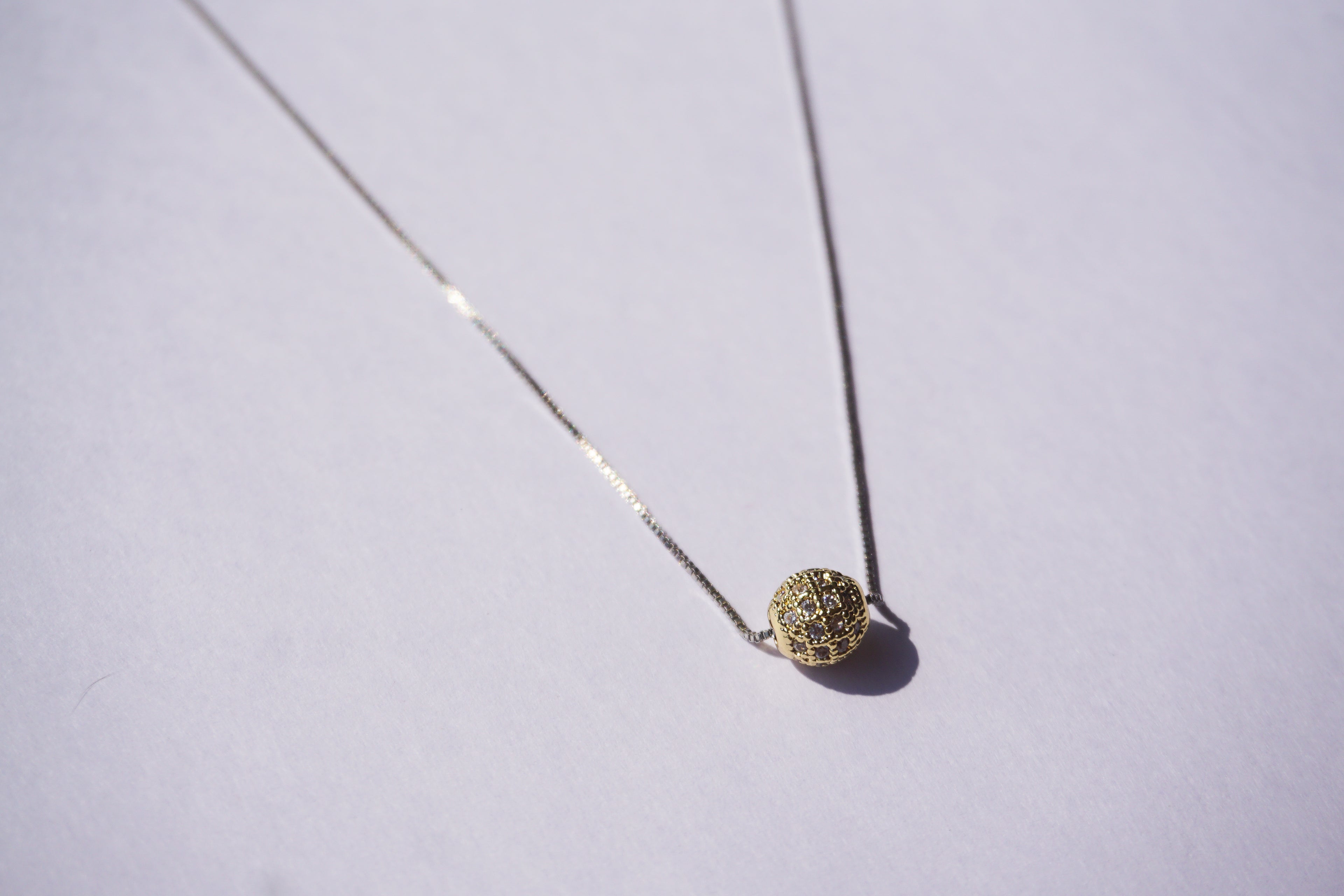 Collar con cadena plateada y bolitas de zirconias doradas