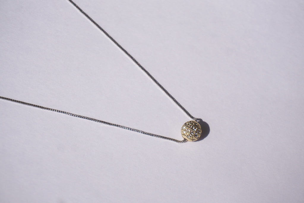 Collar con cadena plateada y bolitas de zirconias doradas