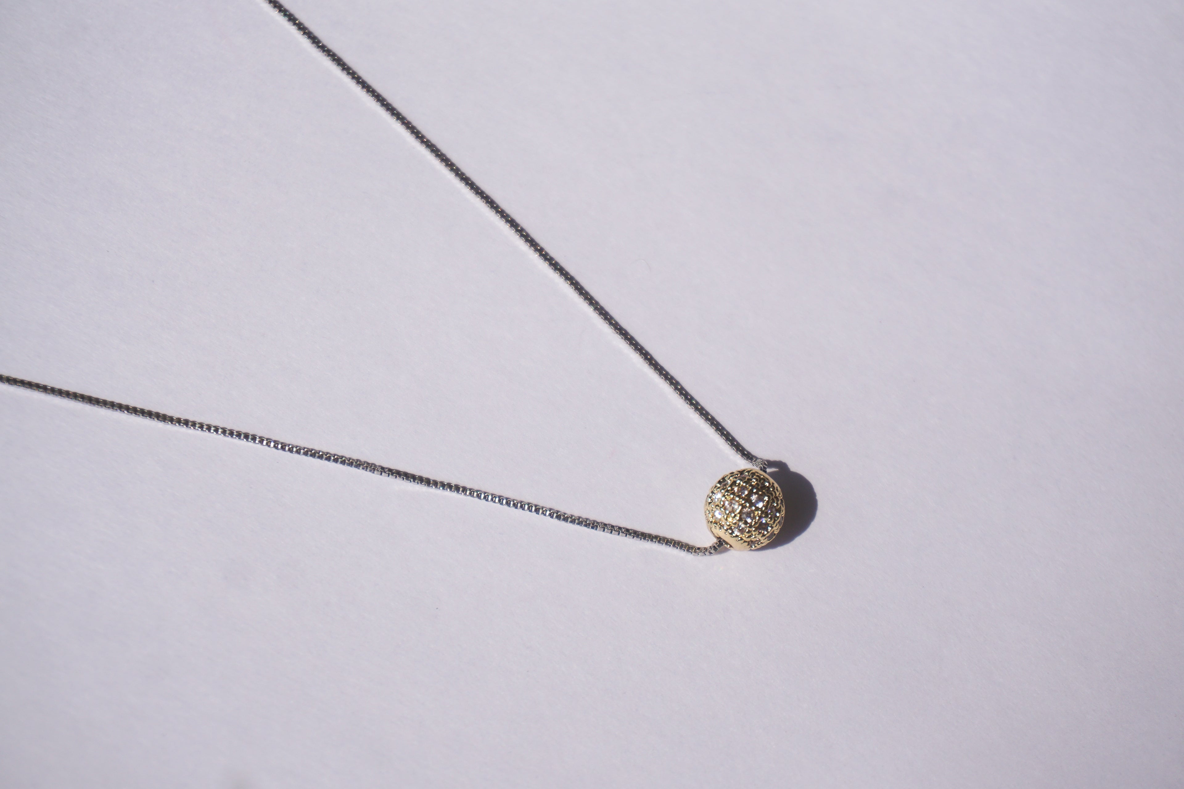 Collar con cadena plateada y bolitas de zirconias doradas