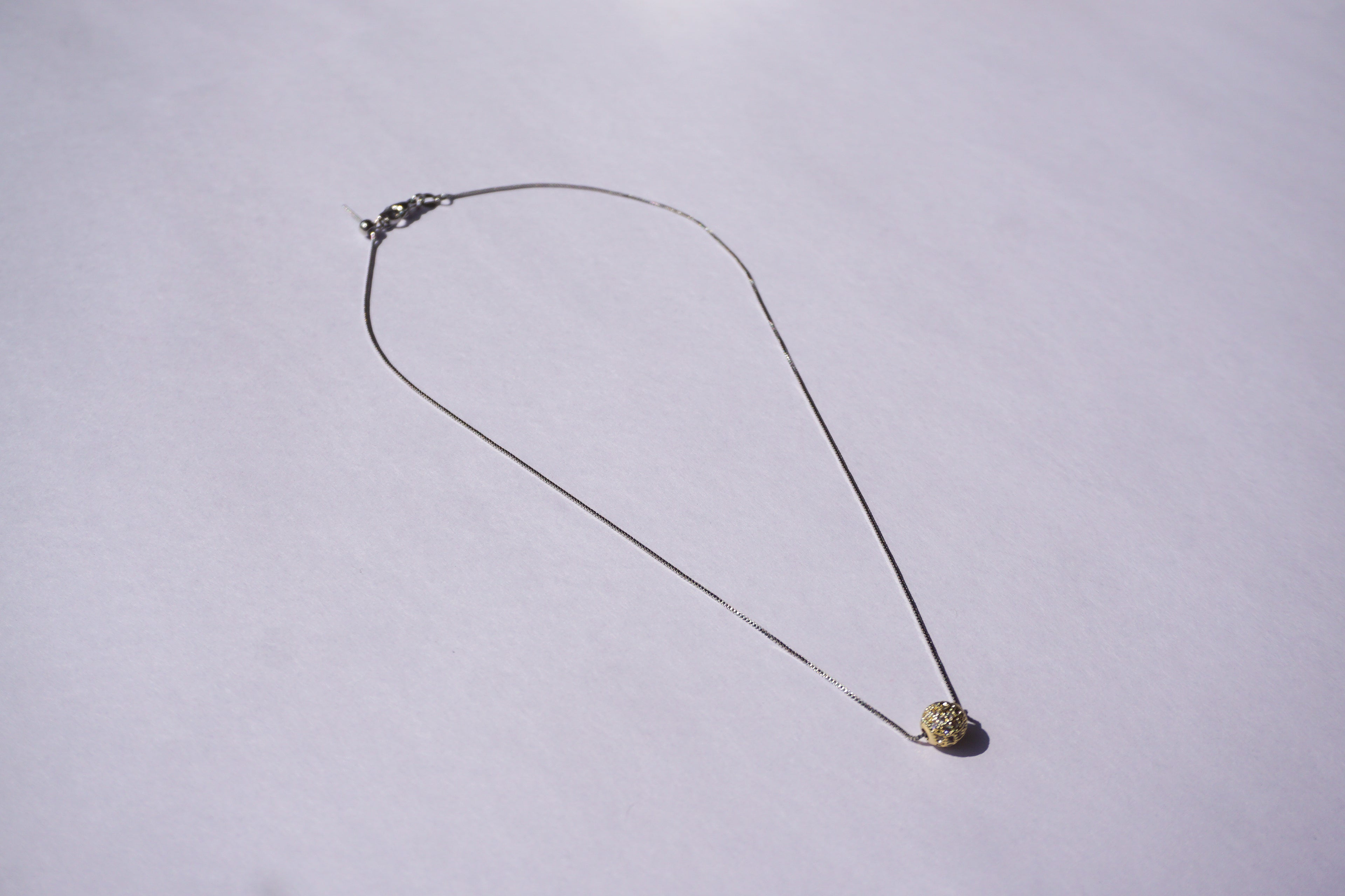 Collar con cadena plateada y bolitas de zirconias doradas