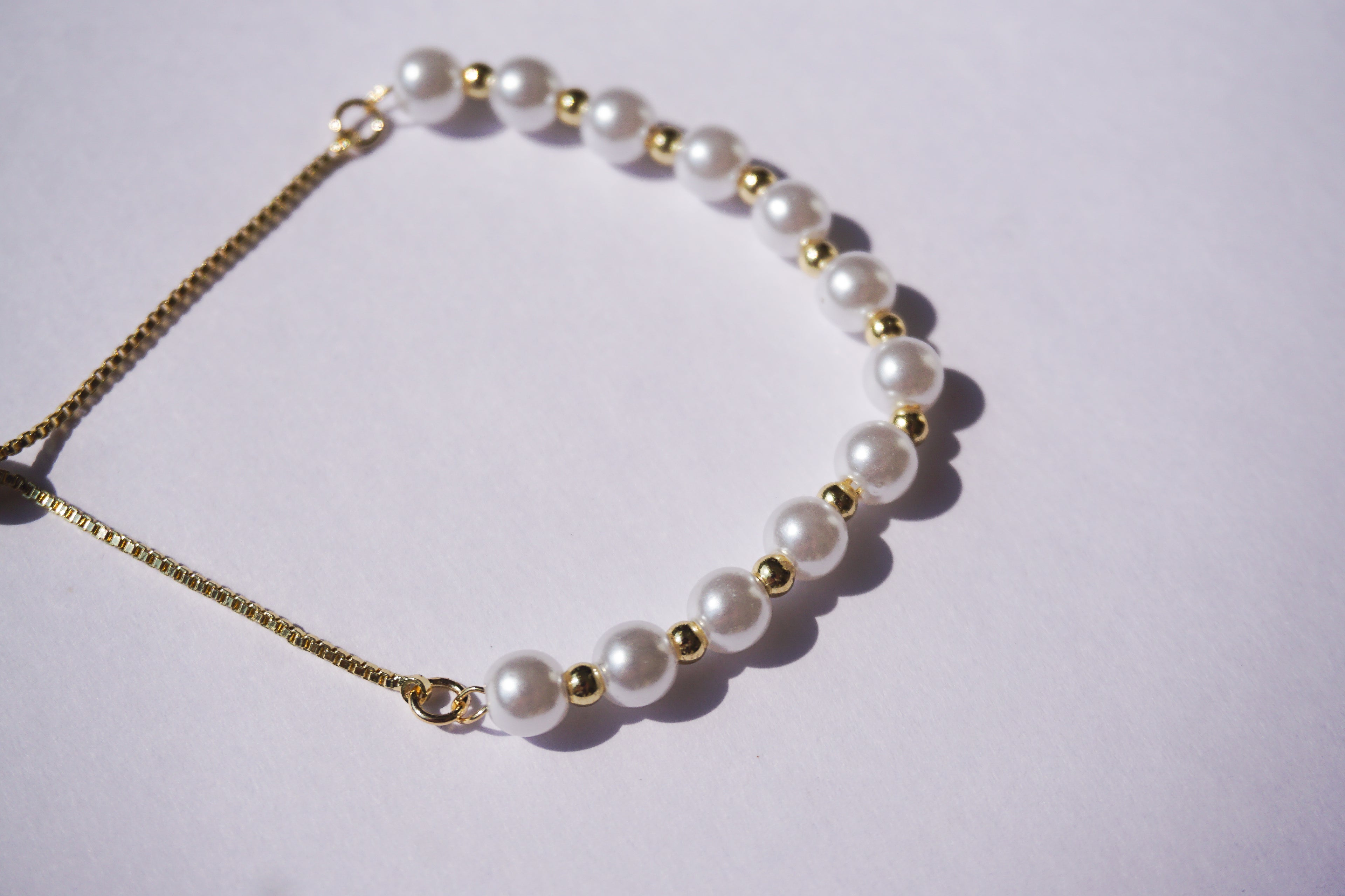 Pulsera perlas con bolita dorada