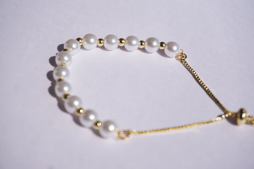 Pulsera perlas con bolita dorada
