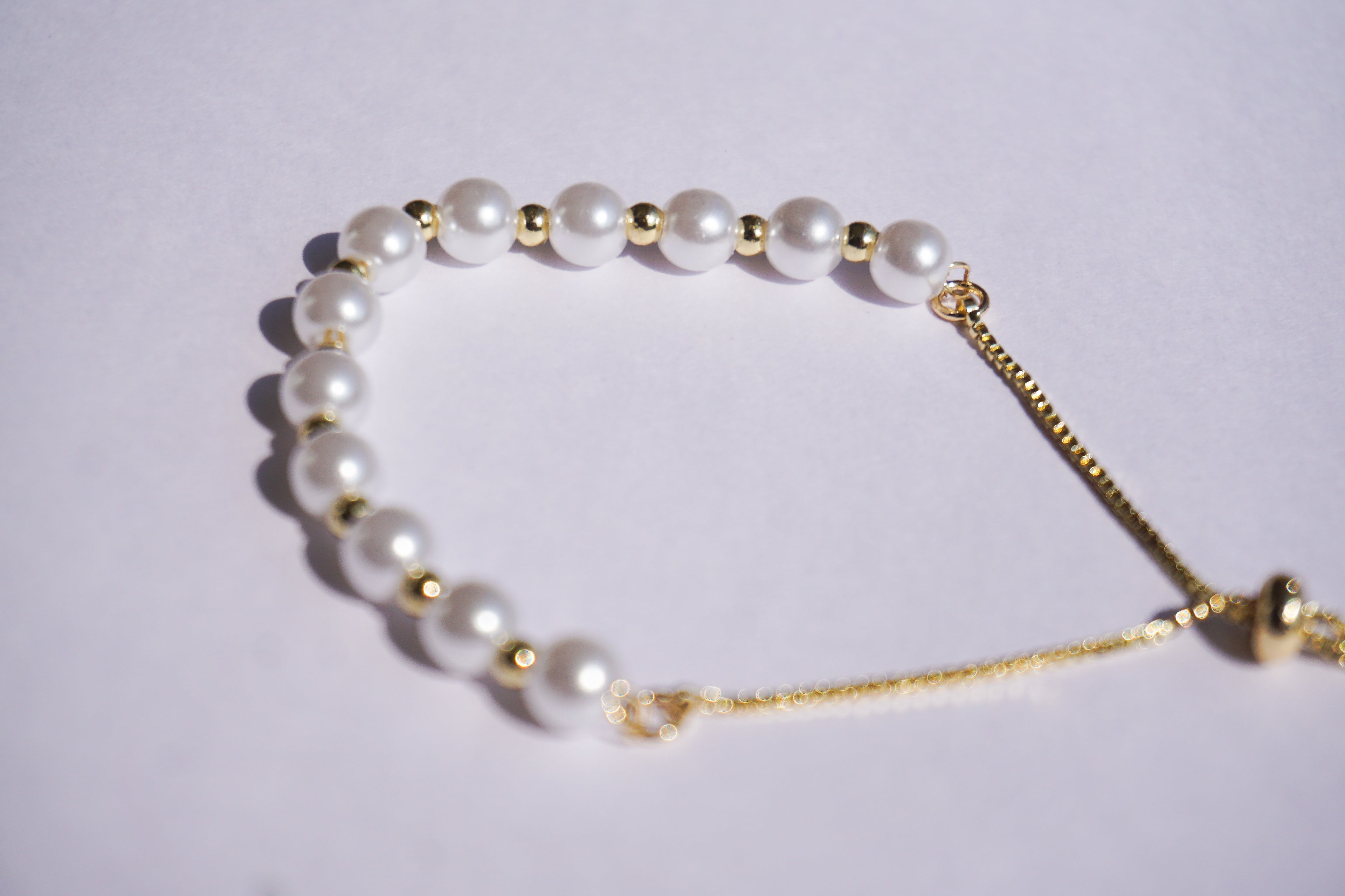 Pulsera perlas con bolita dorada