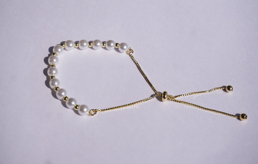 Pulsera perlas con bolita dorada