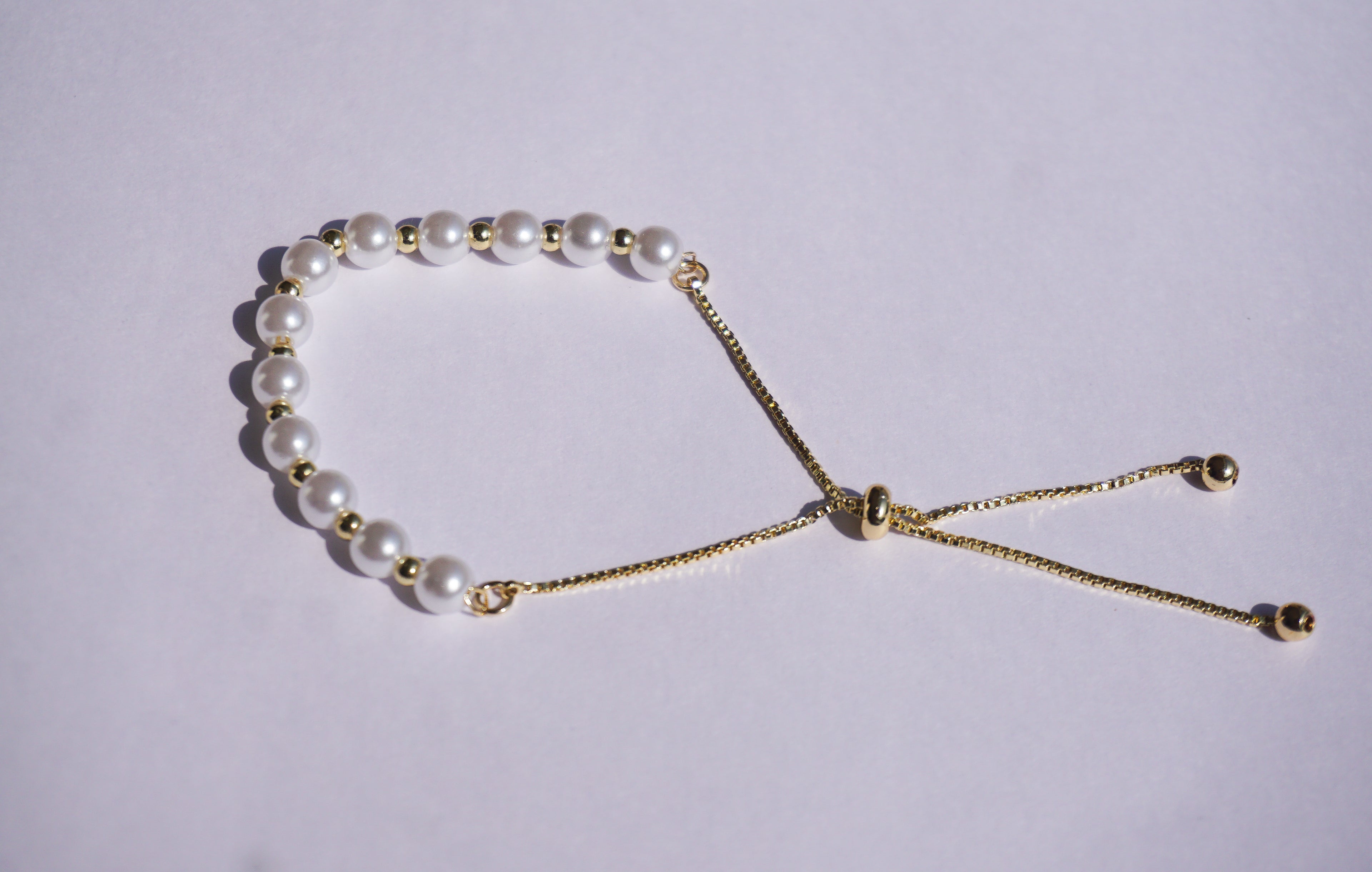 Pulsera perlas con bolita dorada