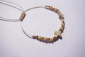 Pulsera de hilo con piedra de cristal y bolita dorada