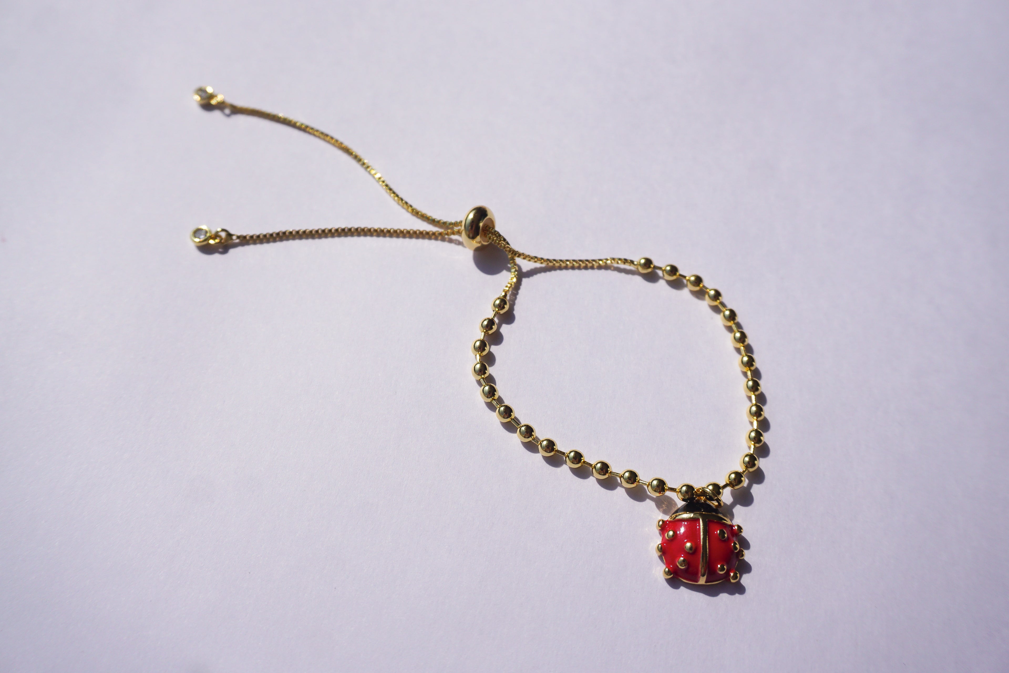 Pulsera con bolitas doradas y catarina