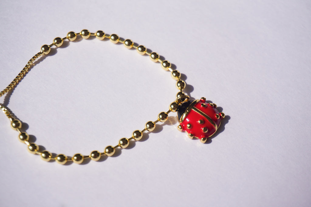 Pulsera con bolitas doradas y catarina