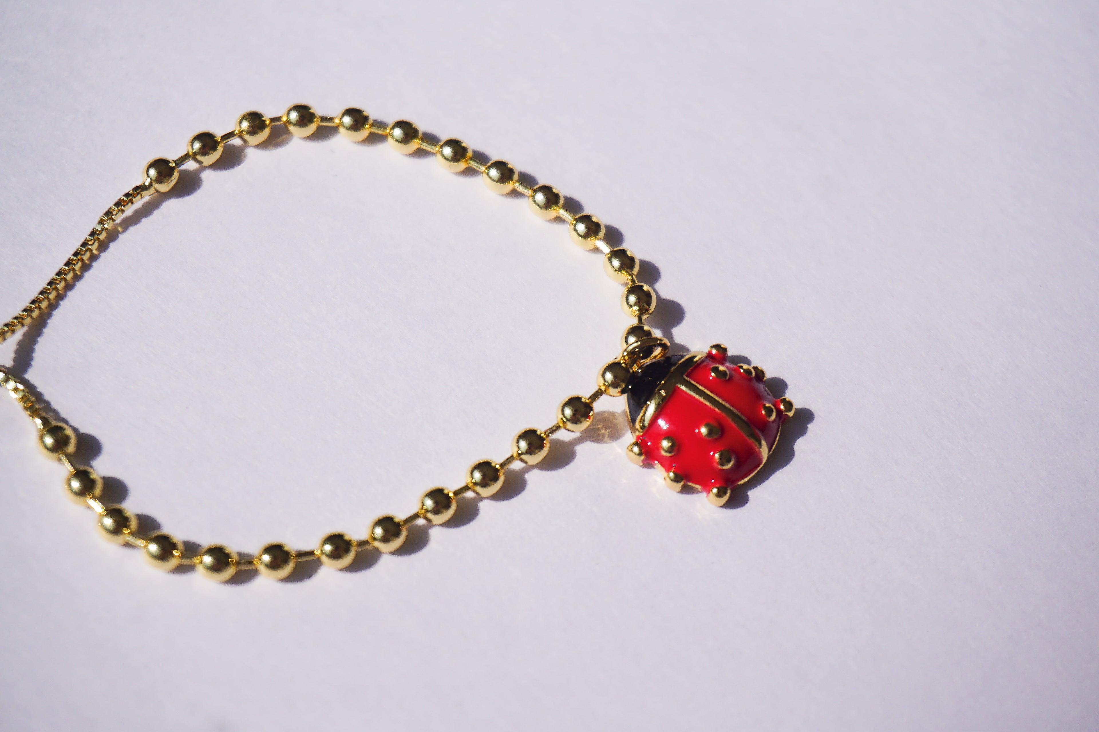 Pulsera con bolitas doradas y catarina