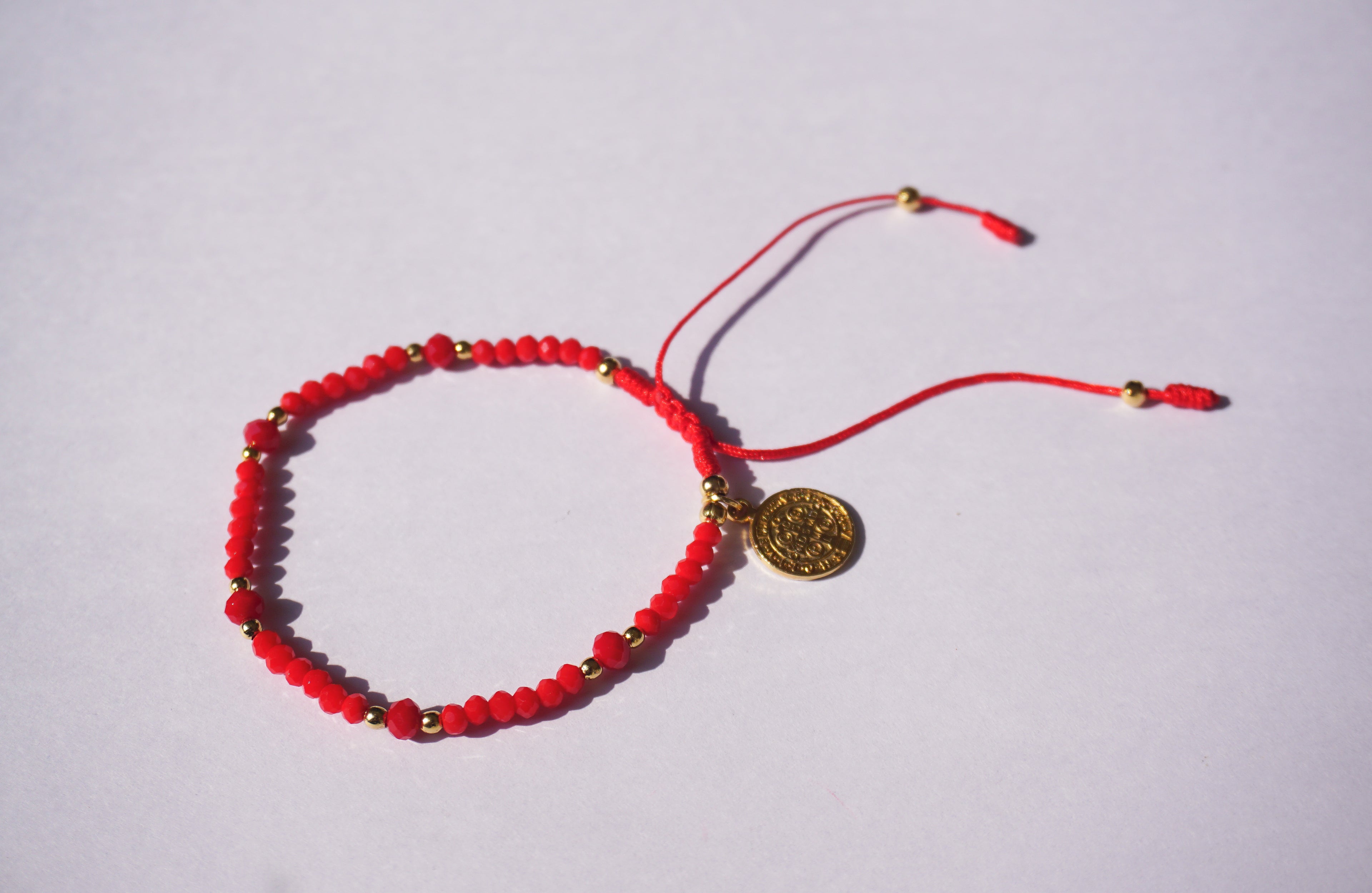 Pulsera de hilo rojo con cristales y San Benito dorado