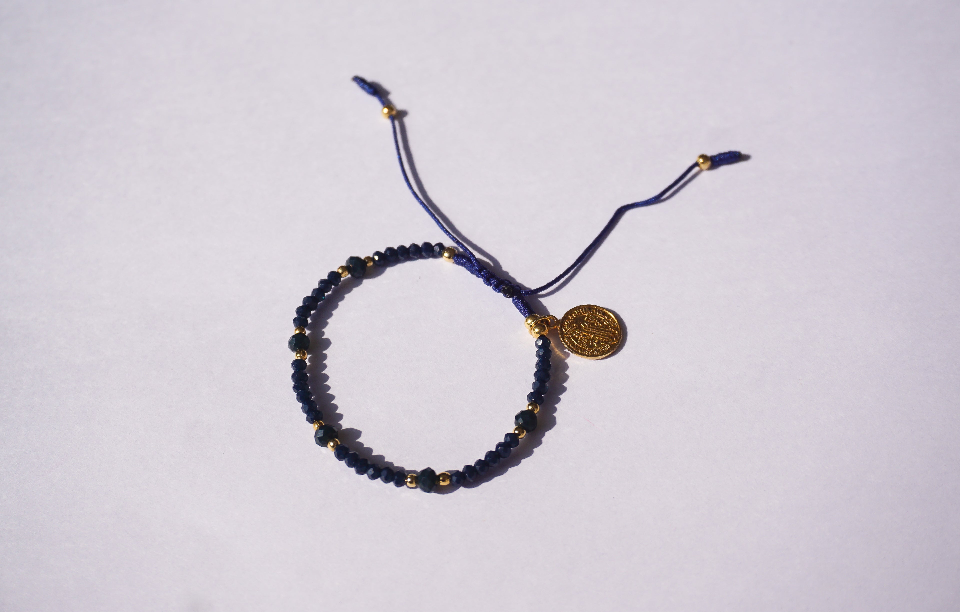 Pulsera de hilo azul con cristales y San Benito dorado