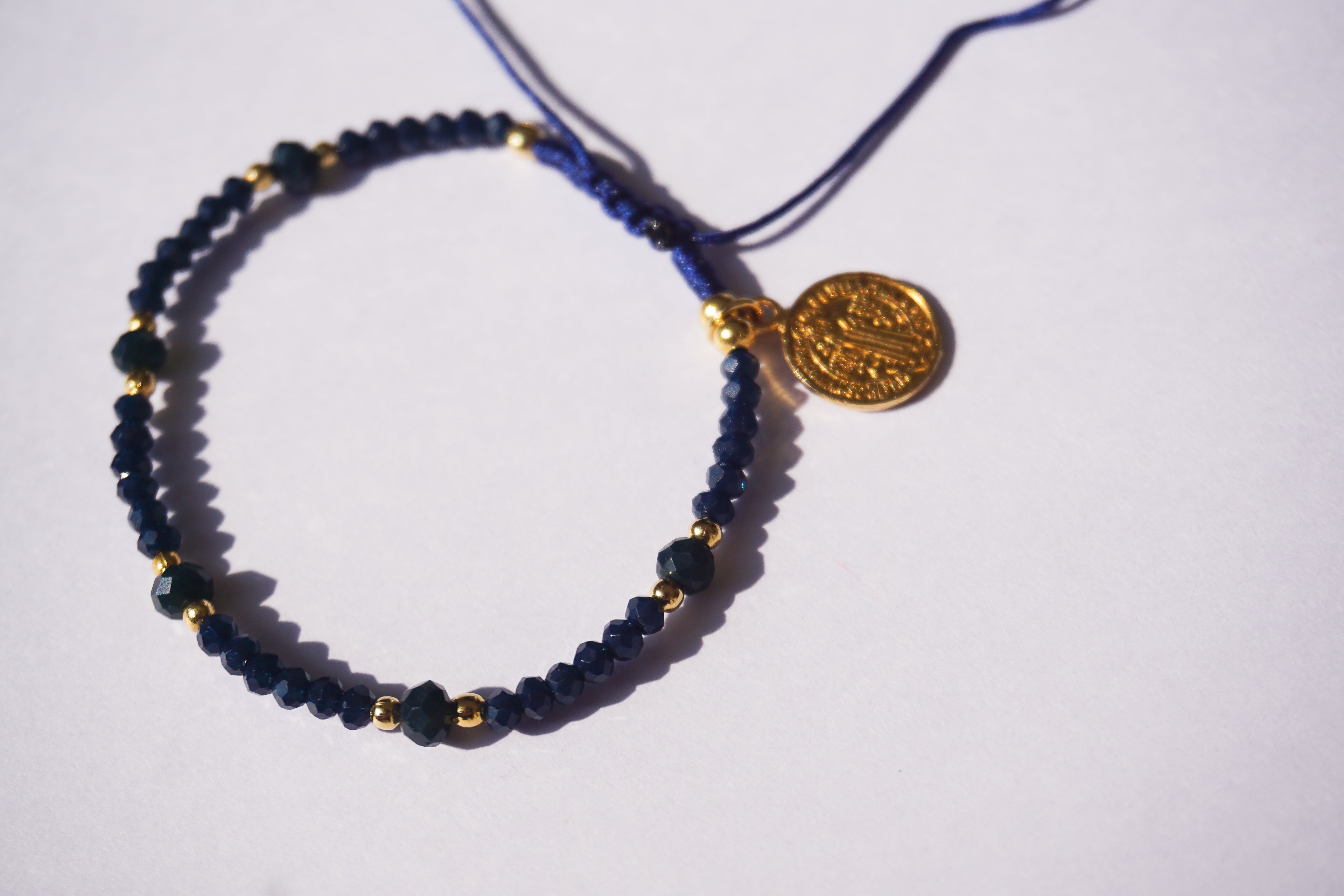 Pulsera de hilo azul con cristales y San Benito dorado