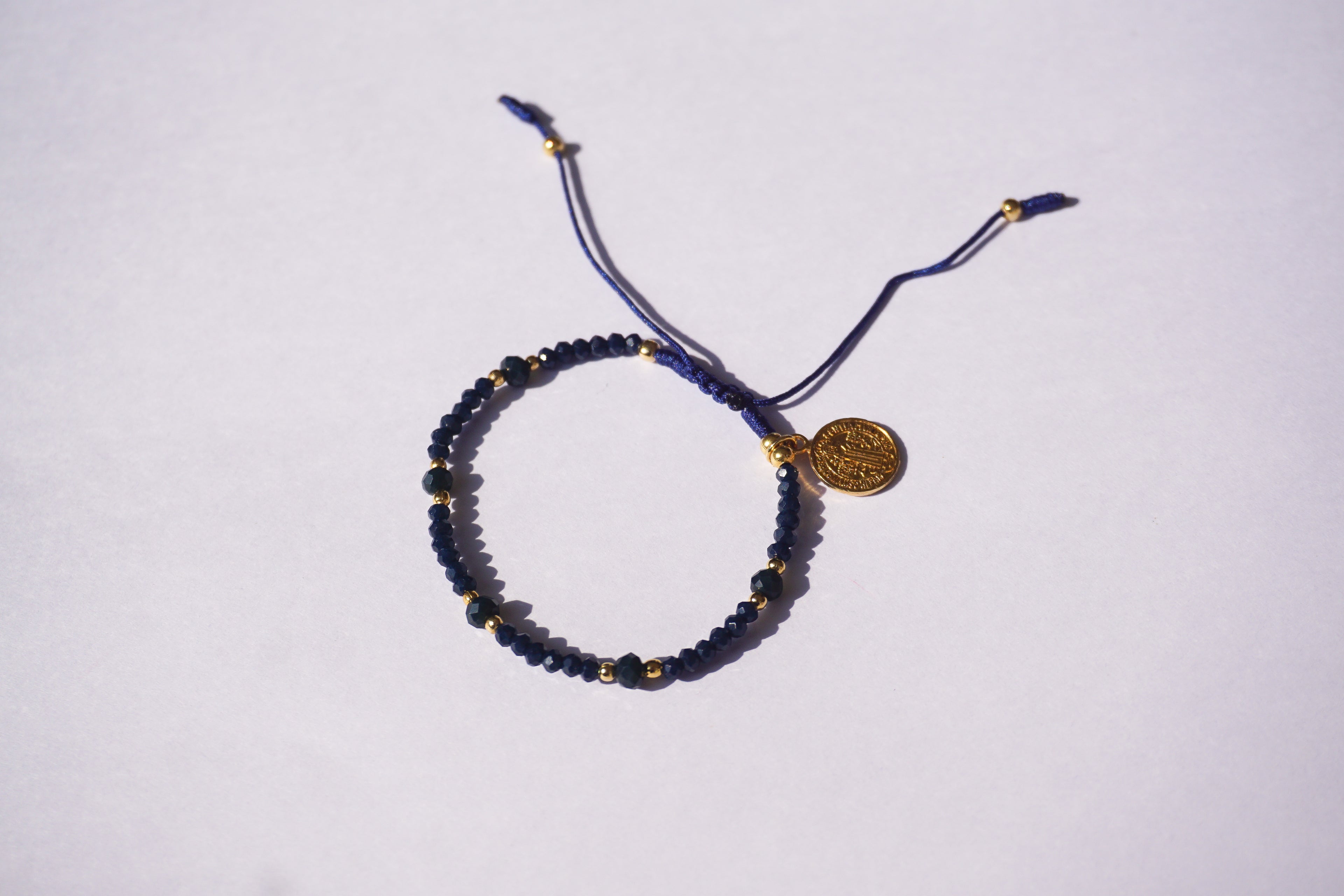 Pulsera de hilo azul con cristales y San Benito dorado