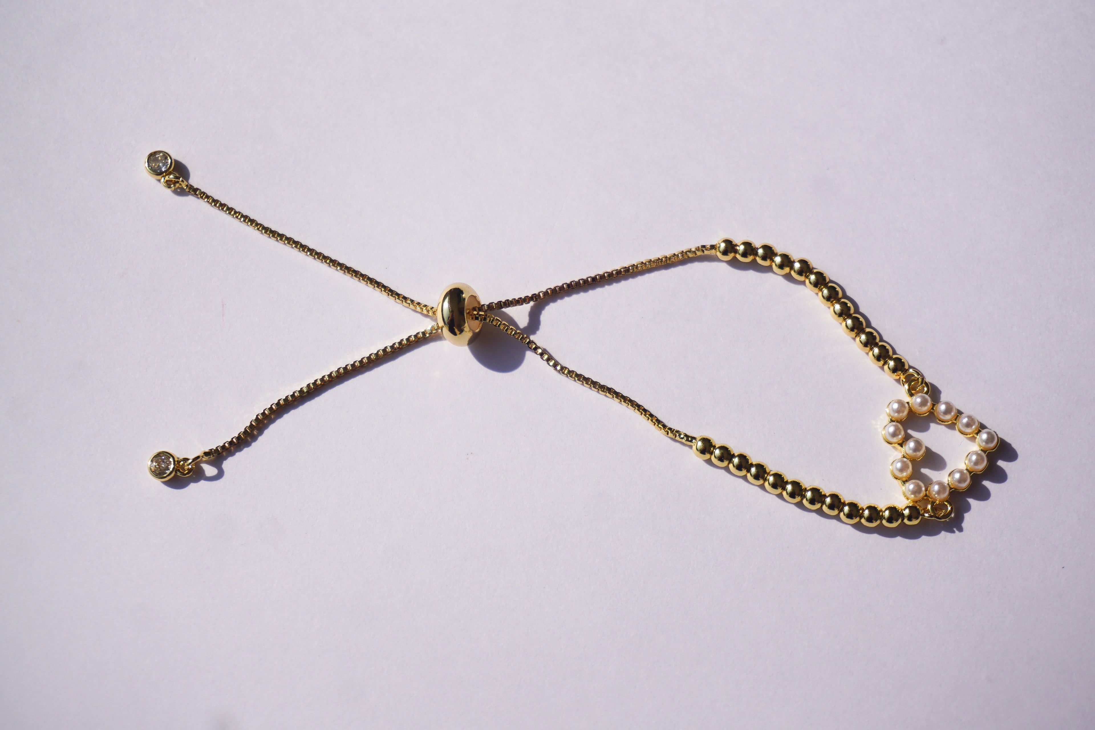 Pulsera dorada con bolitas y corazón de perlitas