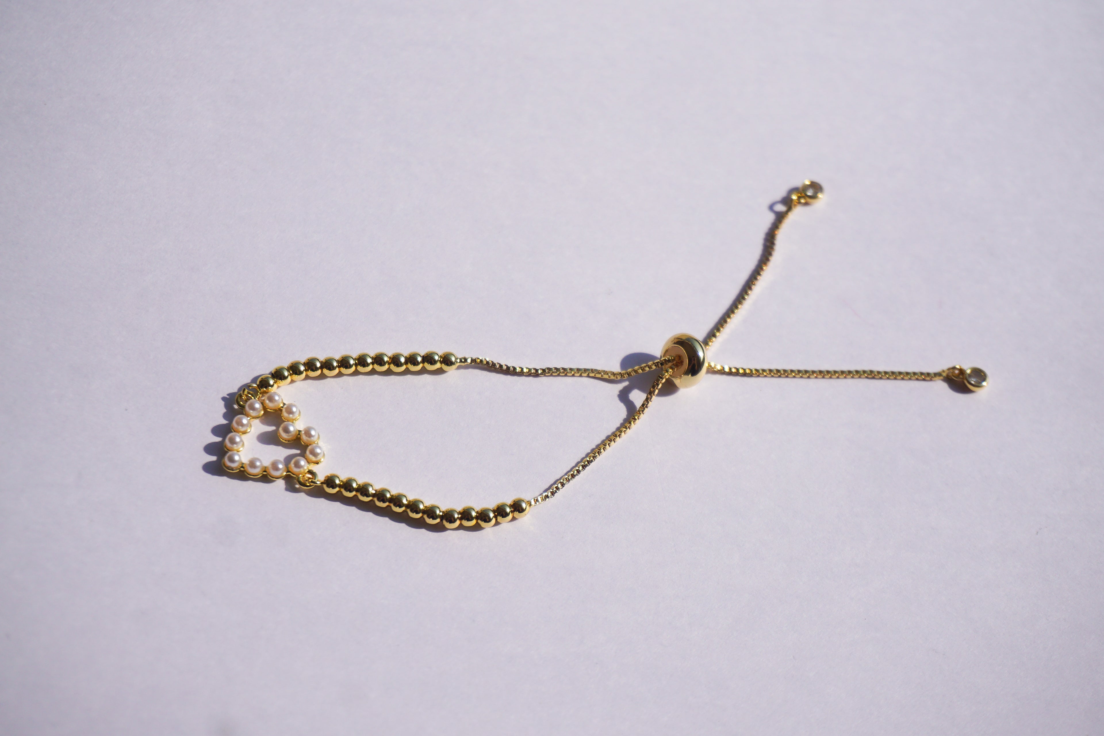 Pulsera dorada con bolitas y corazón de perlitas