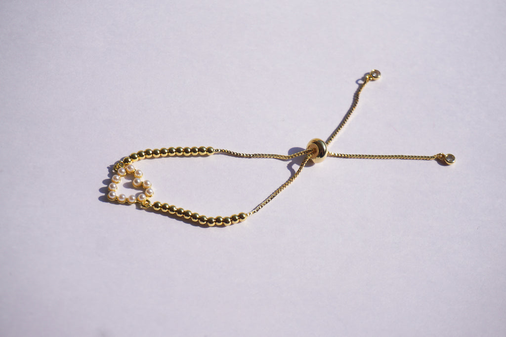 Pulsera dorada con bolitas y corazón de perlitas