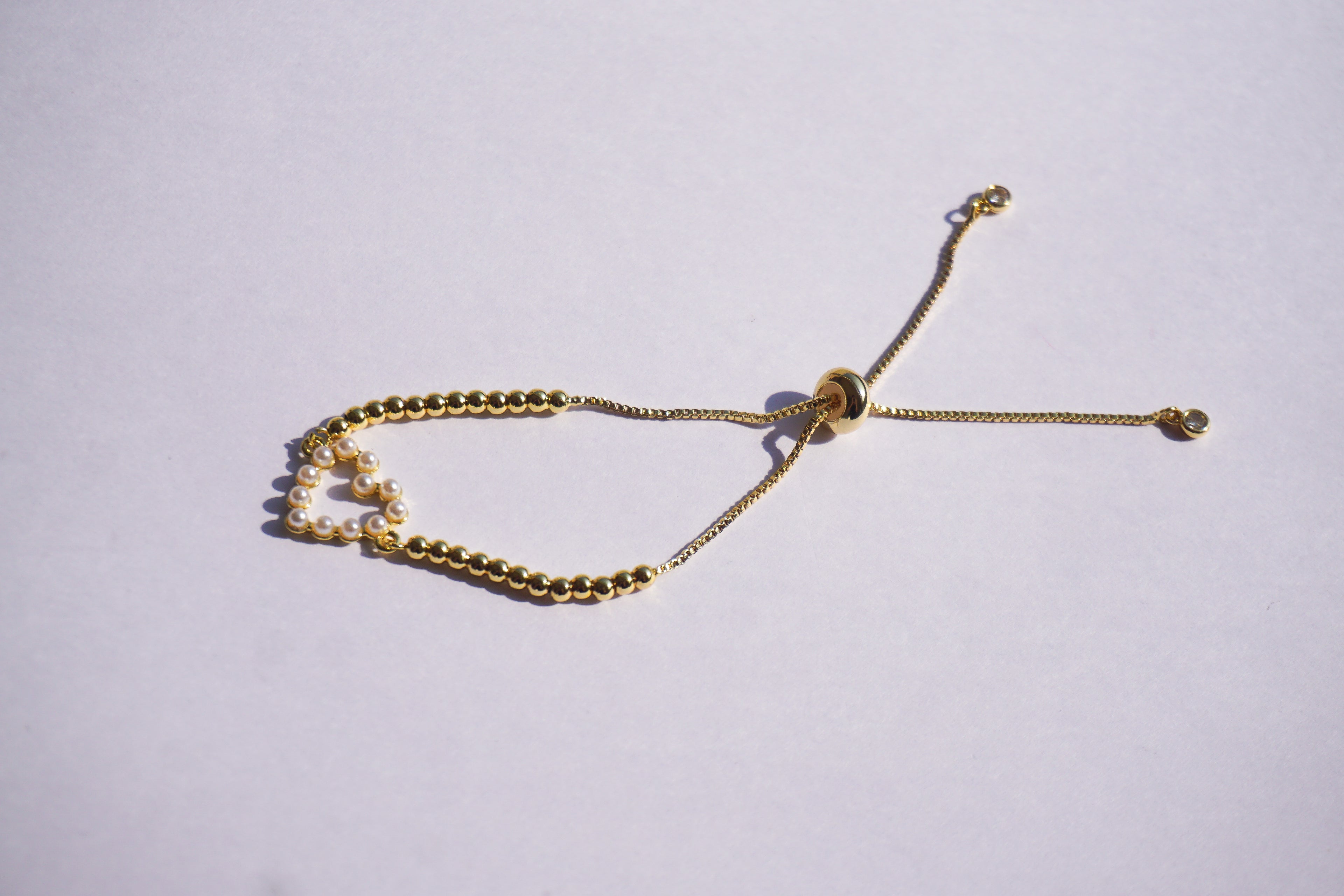 Pulsera dorada con bolitas y corazón de perlitas