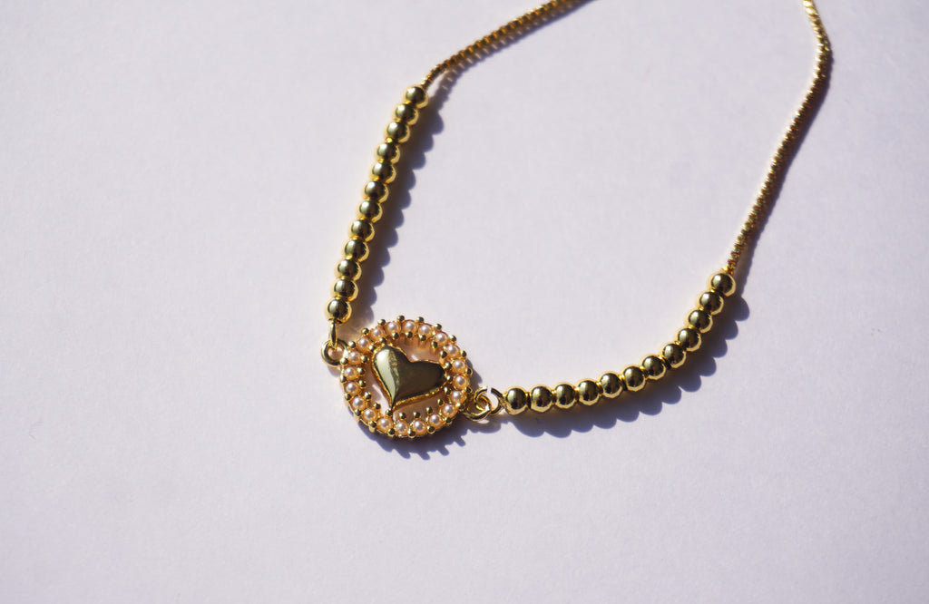 Pulsera dorada con corazón y círculo de perlitas