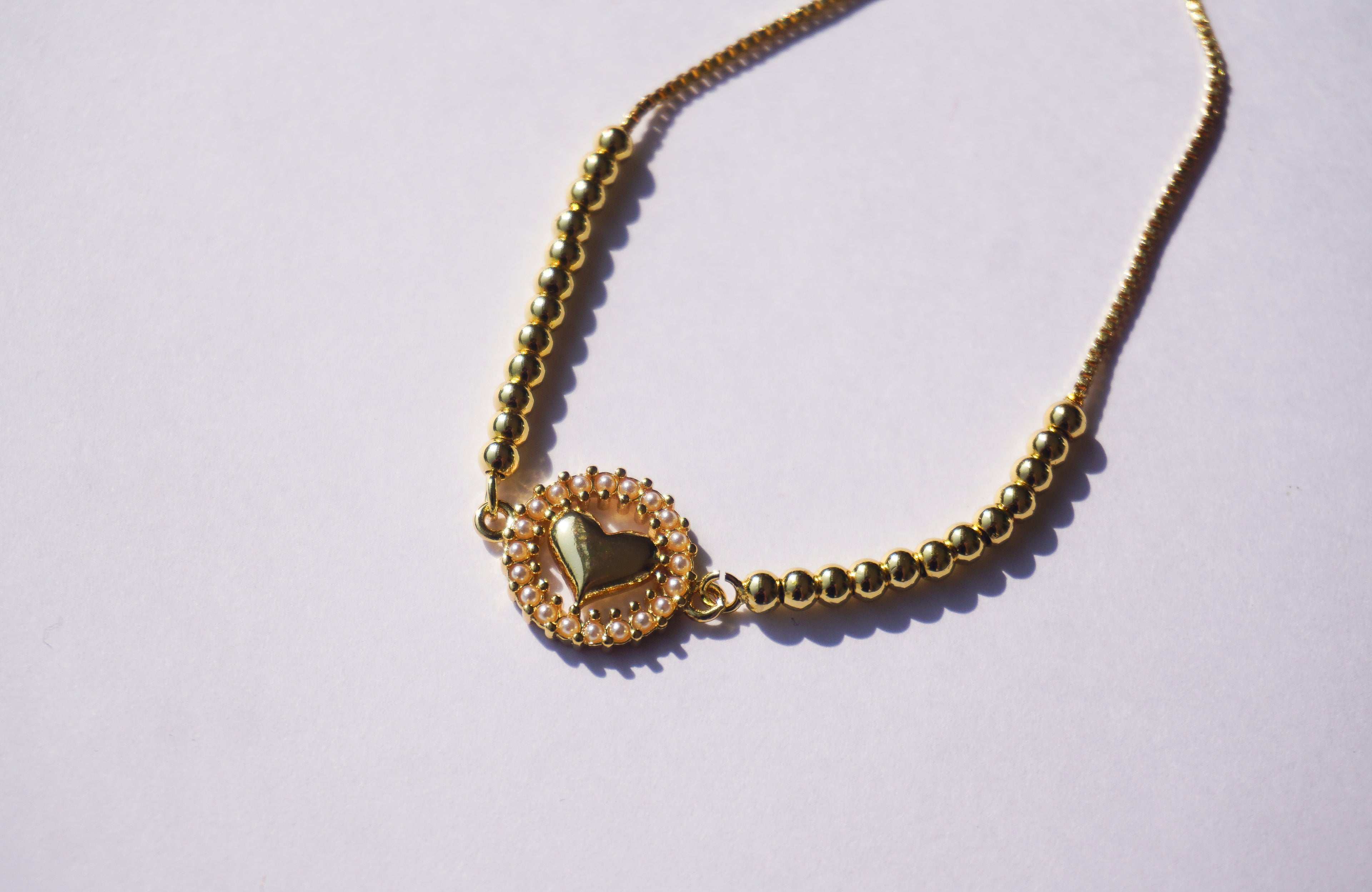 Pulsera dorada con corazón y círculo de perlitas