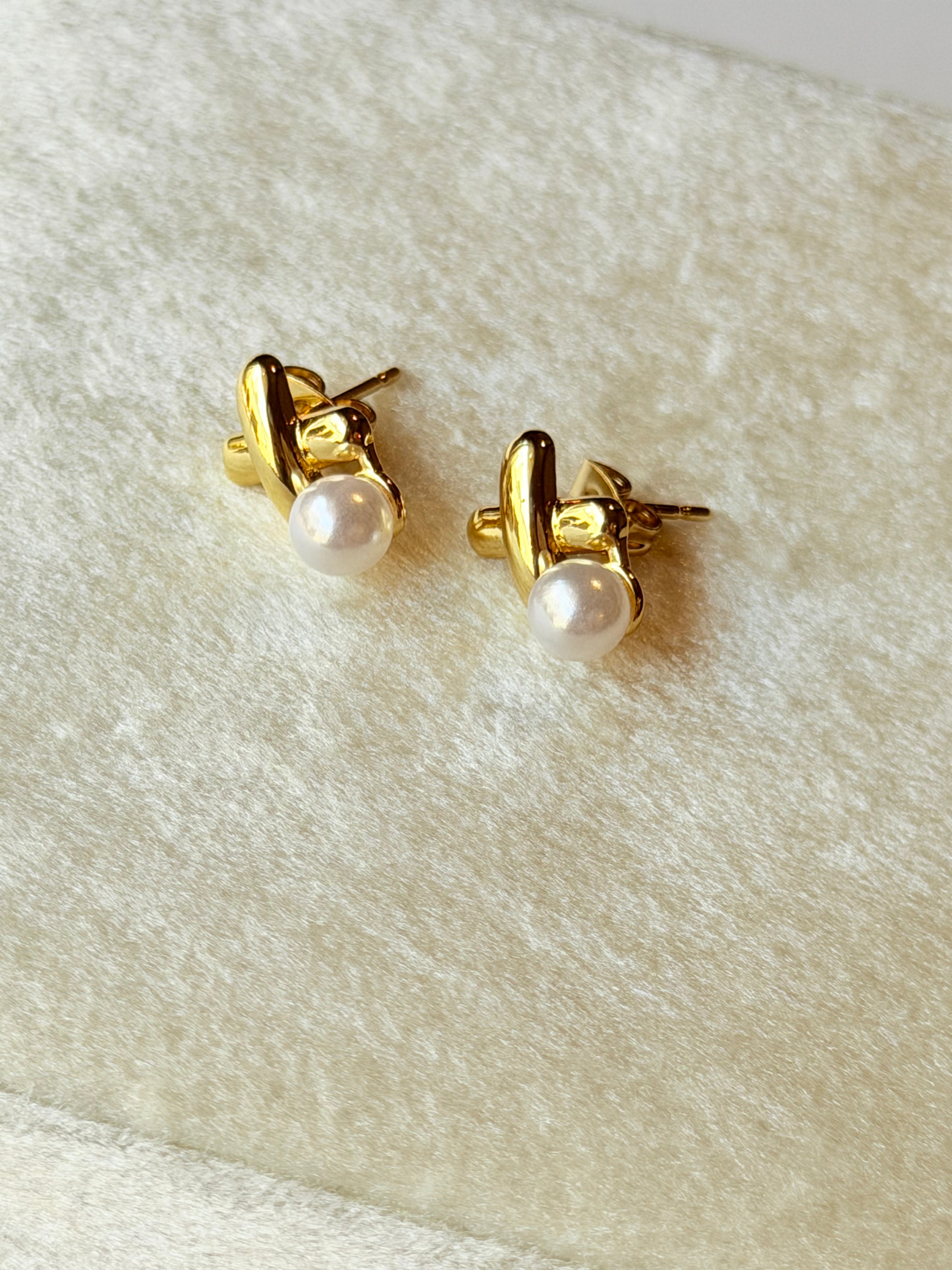 Broquel con X y perla colgante