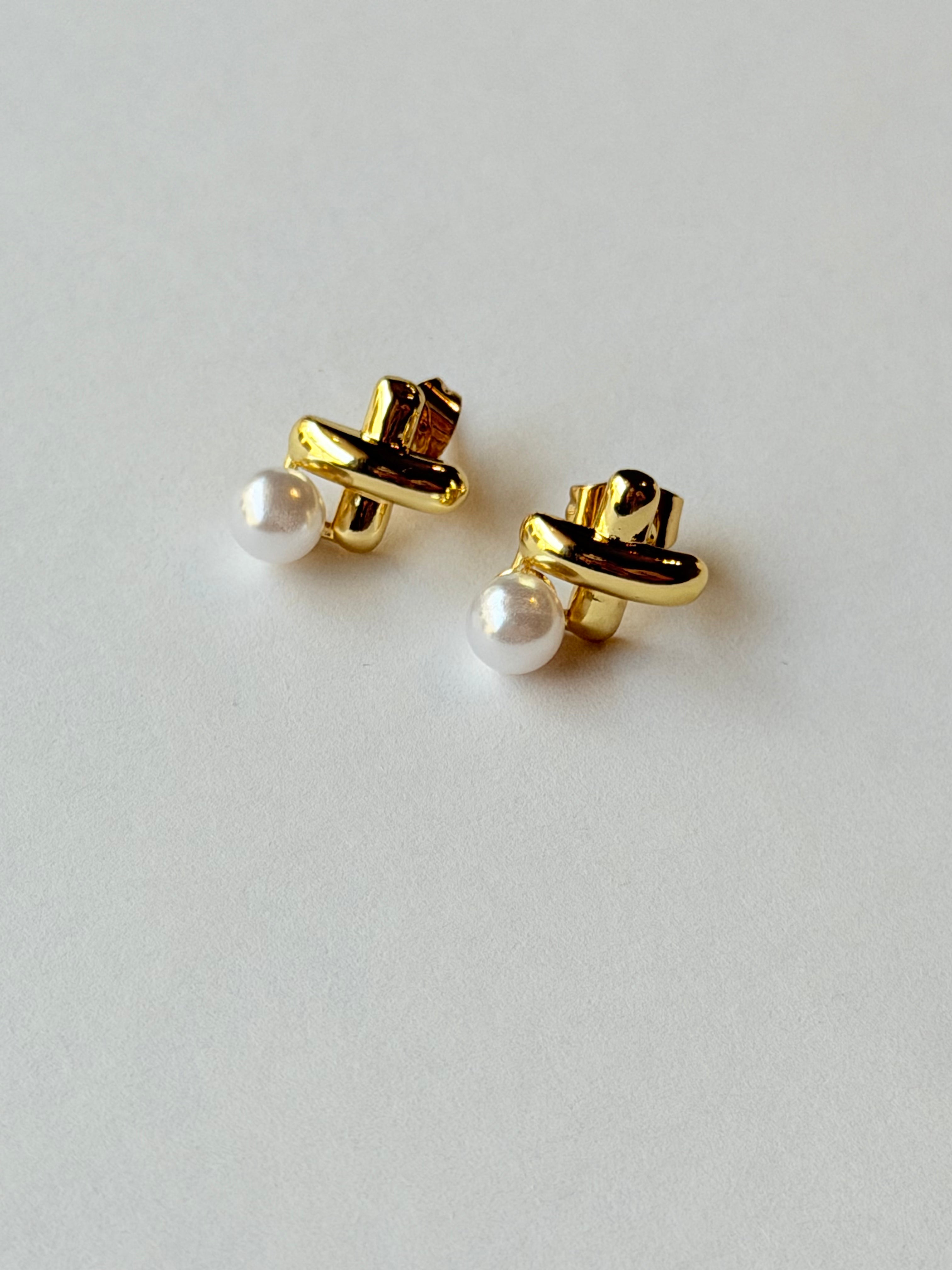 Broquel con X y perla colgante
