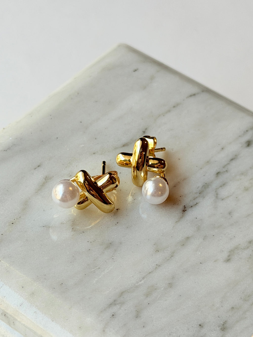 Broquel con X y perla colgante