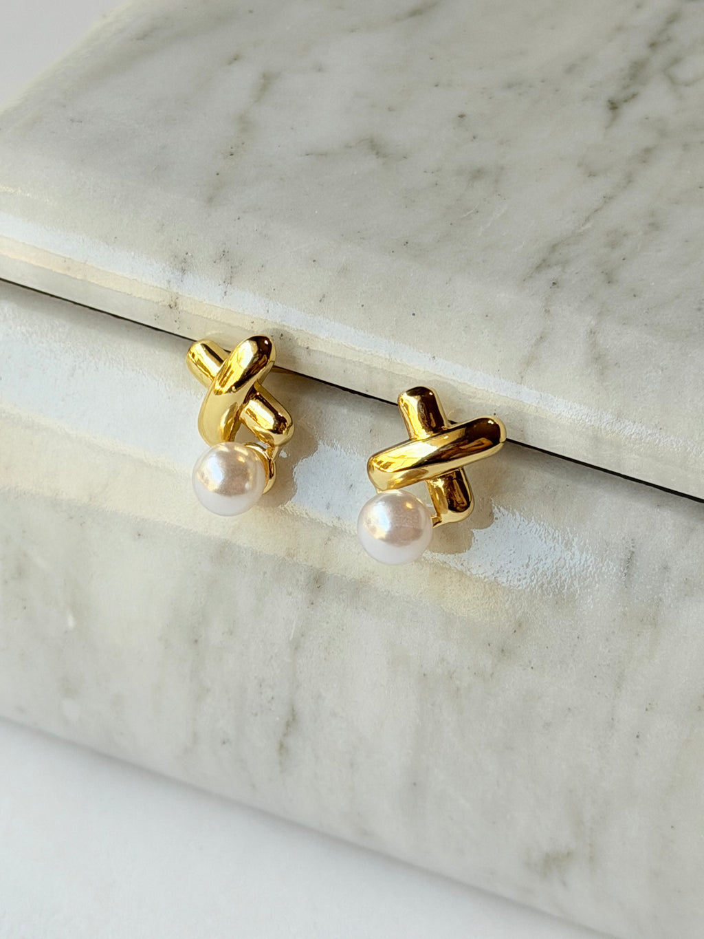 Broquel con X y perla colgante