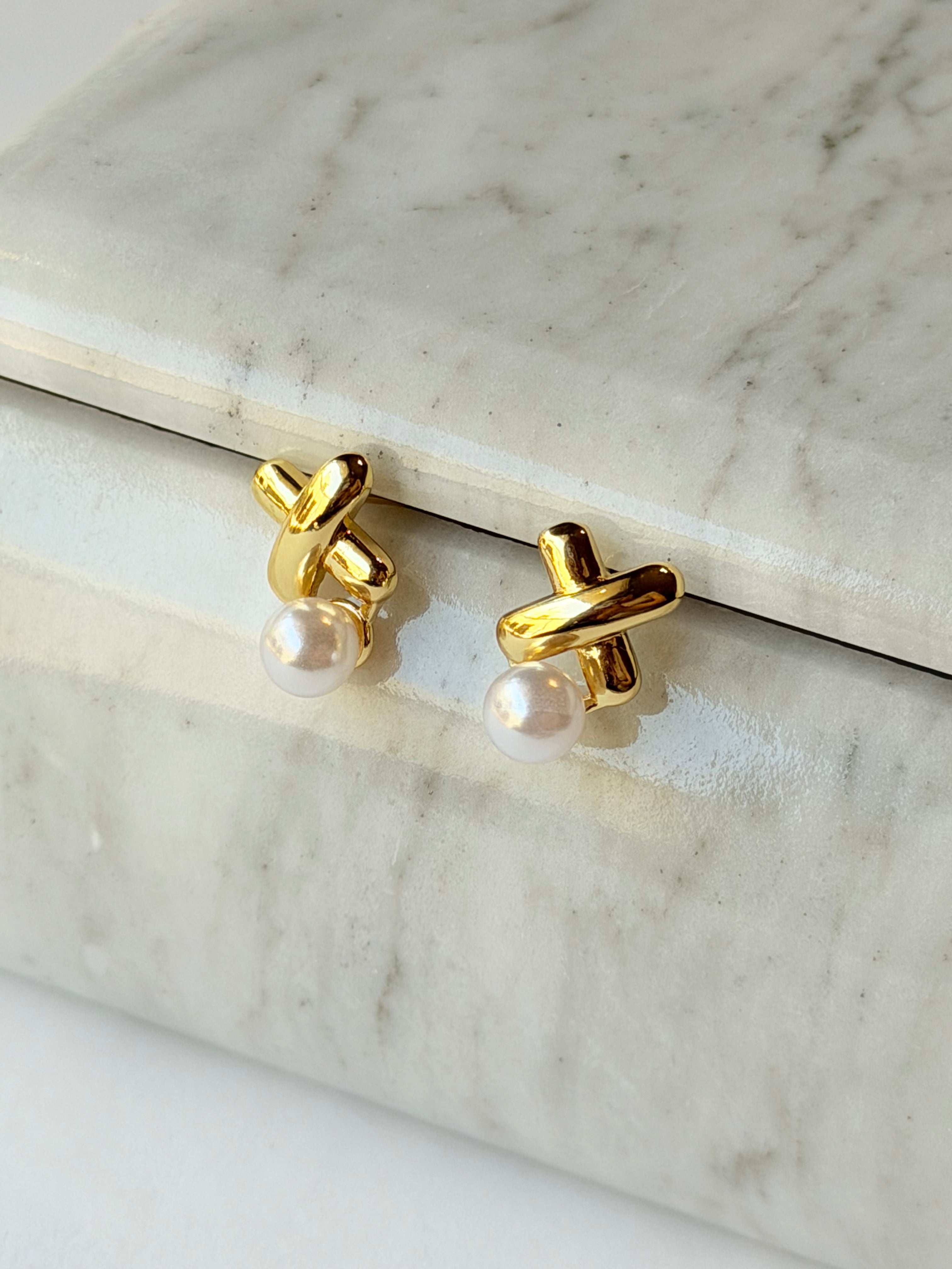 Broquel con X y perla colgante