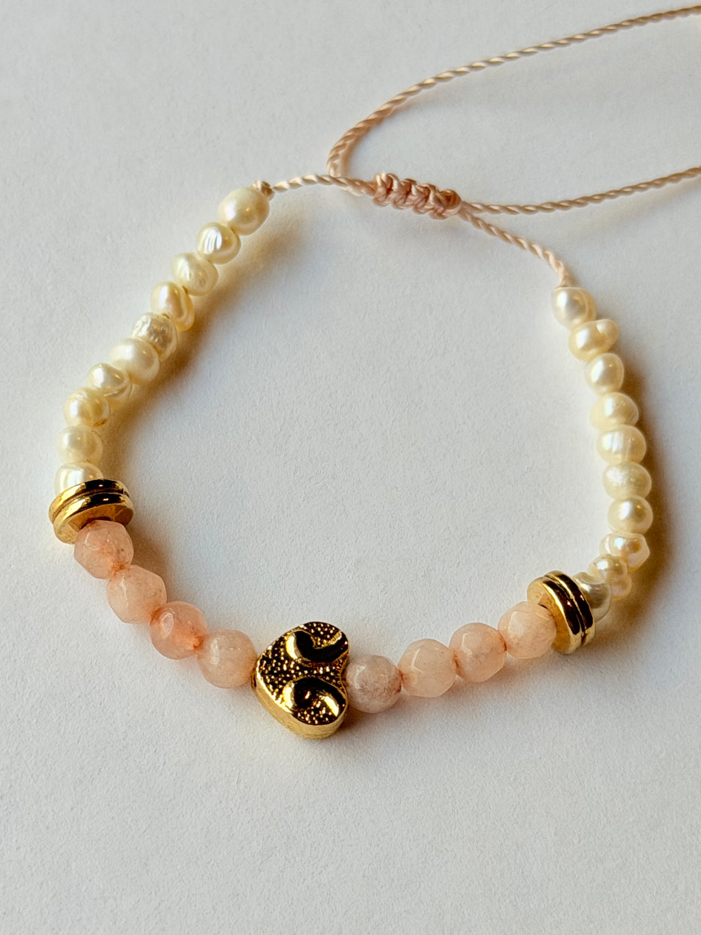 Pulsera de hilo con perlas y cristales rosas con corazón dorado